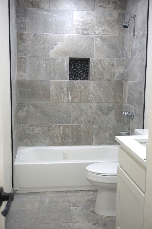 full bathroom featuring toilet, vanity, and tiled shower / bath