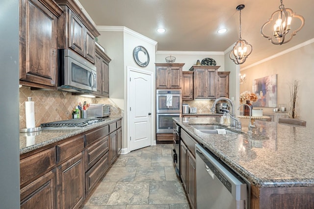 kitchen with sink, hanging light fixtures, backsplash, a kitchen island with sink, and appliances with stainless steel finishes