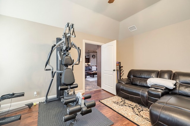 workout area featuring ceiling fan, dark wood-type flooring, and vaulted ceiling