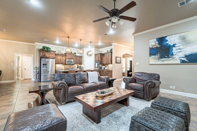 living room featuring ceiling fan, light tile patterned flooring, a textured ceiling, and ornamental molding