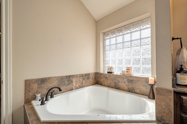 bathroom with a relaxing tiled tub and lofted ceiling