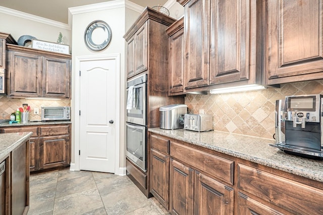 kitchen featuring light stone counters, ornamental molding, double oven, and tasteful backsplash