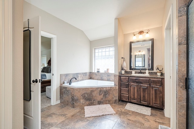 bathroom with vanity, vaulted ceiling, and tiled tub