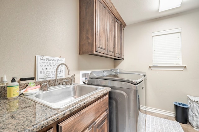 clothes washing area with cabinets, light tile patterned flooring, washer and clothes dryer, and sink