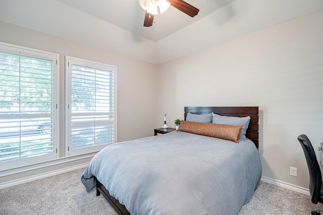 bedroom with a raised ceiling, ceiling fan, and light colored carpet