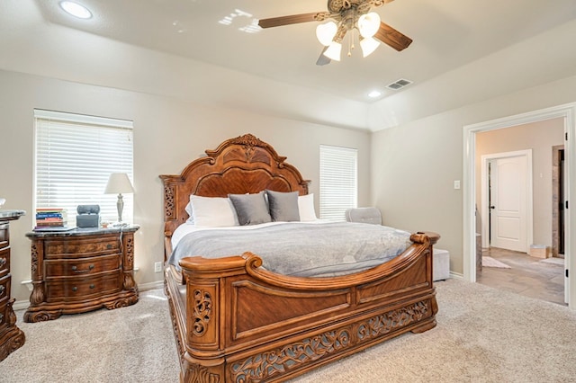 carpeted bedroom with ceiling fan, a tray ceiling, and multiple windows