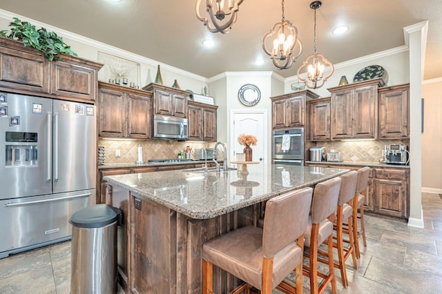 kitchen featuring a chandelier, light stone countertops, an island with sink, and stainless steel appliances