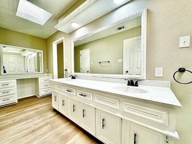 bathroom featuring hardwood / wood-style flooring, vanity, and a skylight