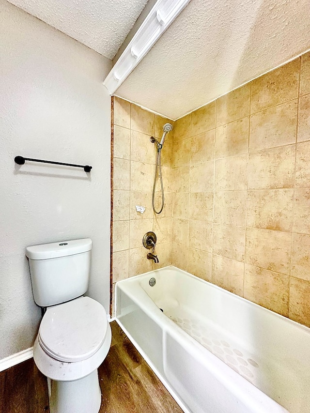 bathroom featuring hardwood / wood-style floors, tiled shower / bath, toilet, and a textured ceiling