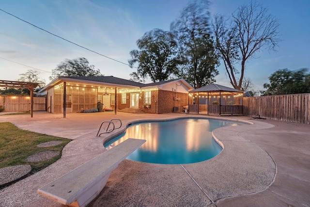 pool at dusk featuring a gazebo and a patio