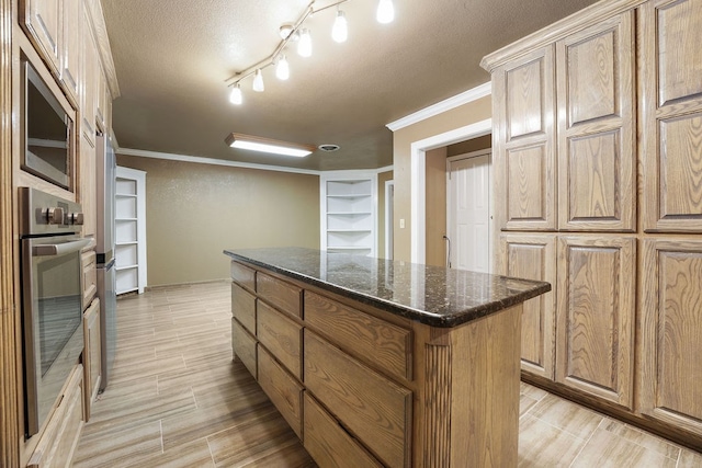 kitchen with a textured ceiling, stainless steel appliances, crown molding, dark stone countertops, and a kitchen island