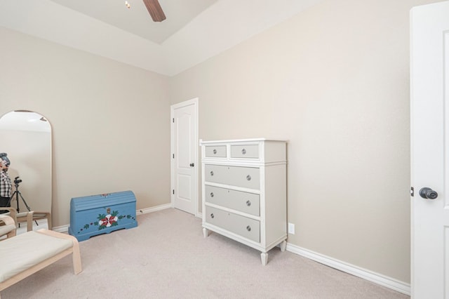 living area with baseboards, a ceiling fan, and light colored carpet