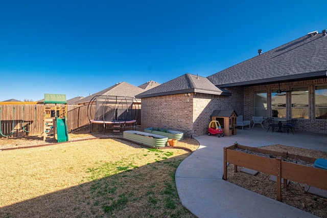 view of yard with a trampoline, a patio area, fence, and a playground