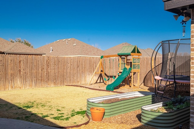 view of jungle gym with a trampoline and a fenced backyard