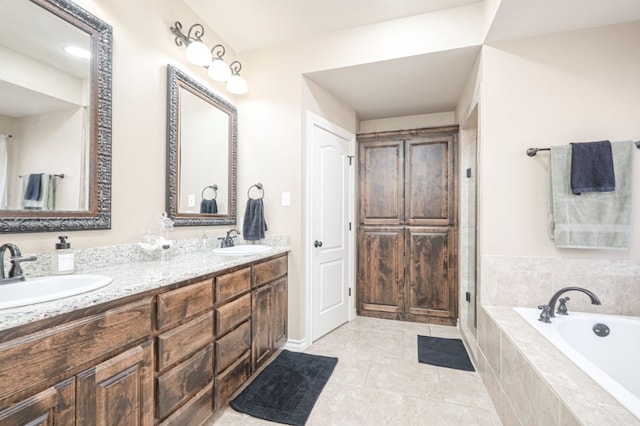 full bath featuring a bath, double vanity, a sink, and tile patterned floors