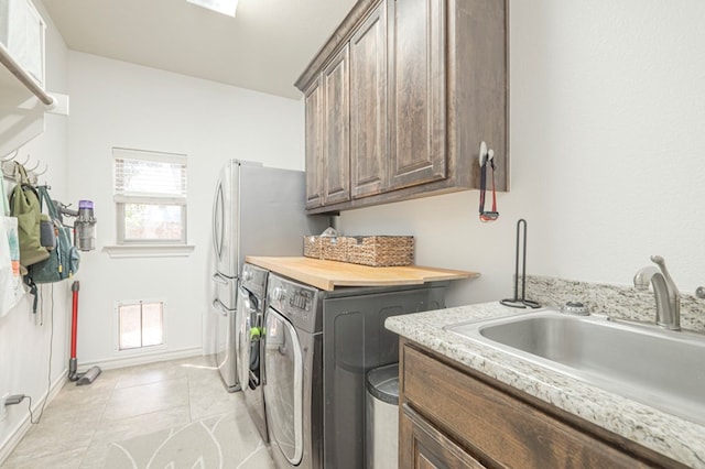 laundry room with light tile patterned floors, cabinet space, visible vents, a sink, and independent washer and dryer