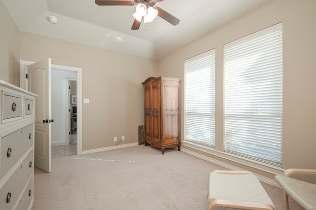 living area with baseboards, vaulted ceiling, a ceiling fan, and light colored carpet