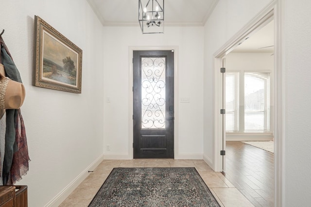 entryway with crown molding, baseboards, and an inviting chandelier