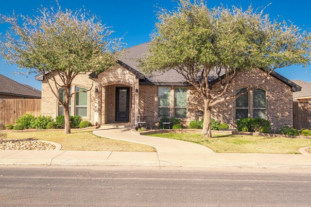 view of front of property featuring brick siding, a front yard, and fence