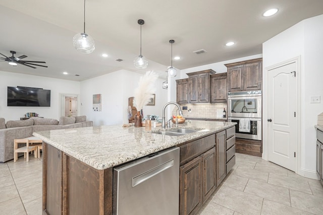 kitchen featuring stainless steel appliances, visible vents, backsplash, a kitchen island with sink, and a sink