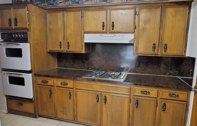 kitchen featuring tasteful backsplash, white double oven, light tile patterned flooring, and stainless steel gas cooktop