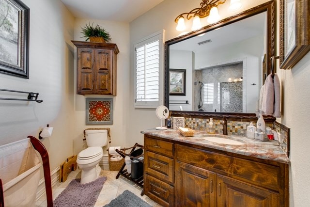 bathroom featuring walk in shower, vanity, tile patterned flooring, toilet, and tasteful backsplash