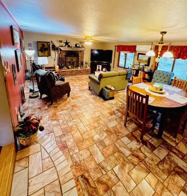 5038 N Sullivan Rd, Fort Stockton, TX 79735 - living area with a textured ceiling, a ceiling fan, and a brick fireplace