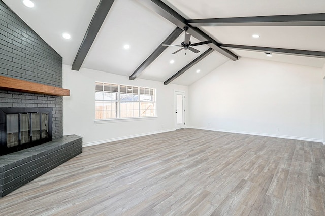 unfurnished living room with lofted ceiling with beams, wood finished floors, a ceiling fan, baseboards, and a brick fireplace