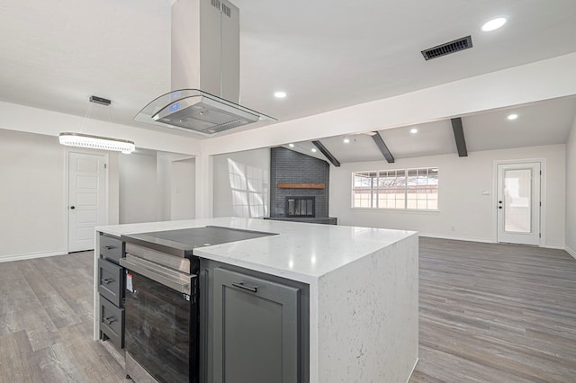 kitchen featuring island exhaust hood, gray cabinets, visible vents, open floor plan, and stainless steel range with electric cooktop