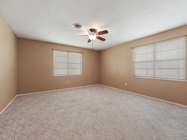 empty room with ceiling fan, light carpet, and a textured ceiling