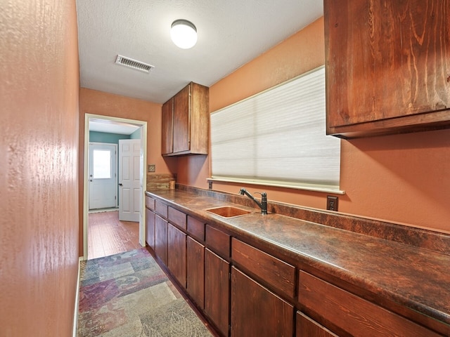 kitchen featuring dark hardwood / wood-style flooring, sink, and a textured ceiling