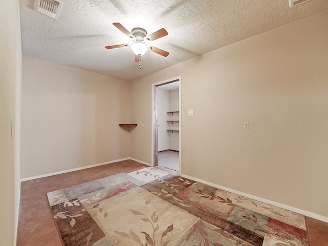 empty room with ceiling fan and a textured ceiling