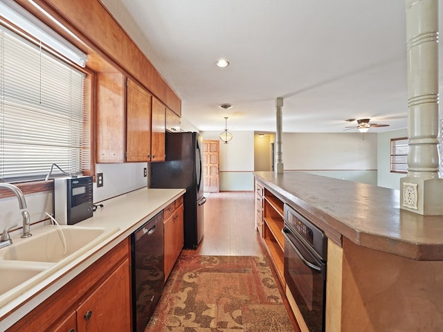 kitchen featuring decorative light fixtures, sink, dark hardwood / wood-style flooring, ceiling fan, and black appliances