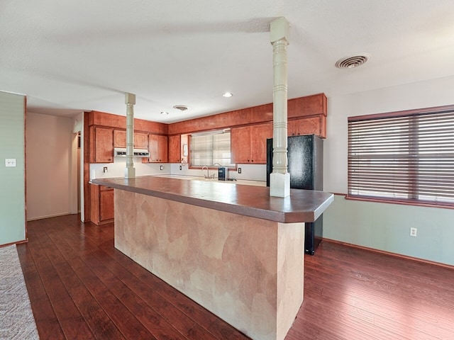 kitchen featuring dark wood-type flooring, sink, decorative columns, and a kitchen island