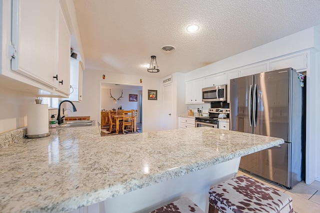 kitchen with sink, stainless steel appliances, kitchen peninsula, and white cabinets