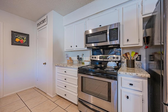 kitchen with stainless steel appliances, a textured ceiling, white cabinets, and light stone counters