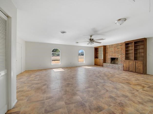 unfurnished living room with built in features, a brick fireplace, and ceiling fan