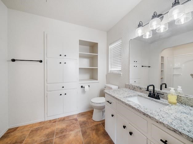 bathroom with built in shelves, vanity, and toilet