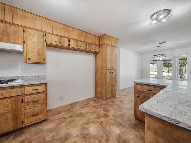 kitchen featuring pendant lighting, stainless steel gas stovetop, an inviting chandelier, light stone countertops, and extractor fan