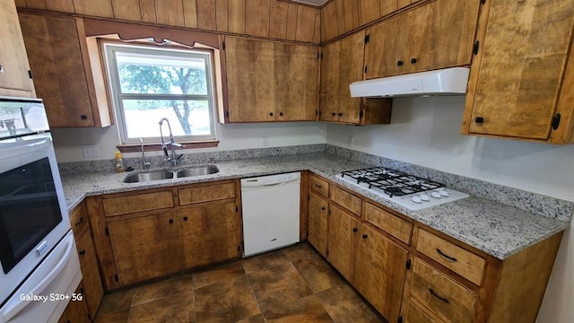 kitchen featuring sink, white appliances, light stone countertops, and range hood