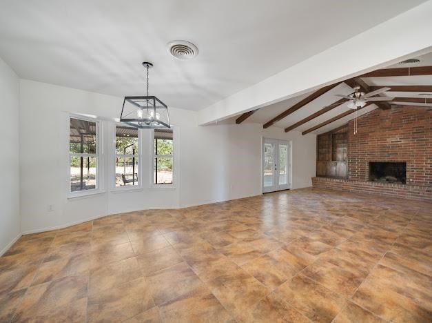 unfurnished living room with a fireplace, french doors, vaulted ceiling with beams, and ceiling fan