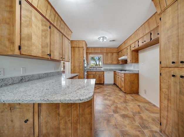 kitchen with light stone countertops, sink, kitchen peninsula, stovetop, and white dishwasher