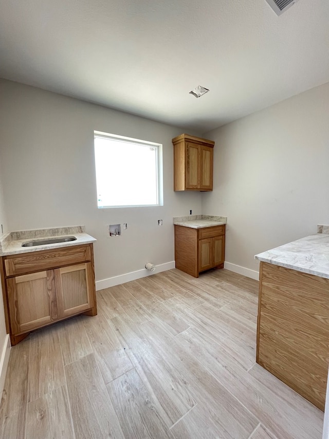 washroom featuring cabinet space, baseboards, a sink, and hookup for a washing machine