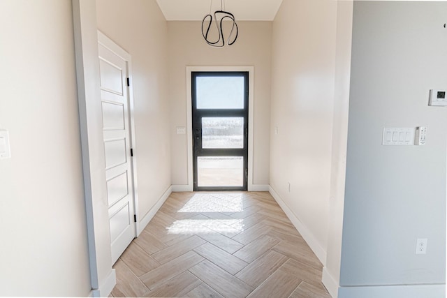 doorway with baseboards and a chandelier