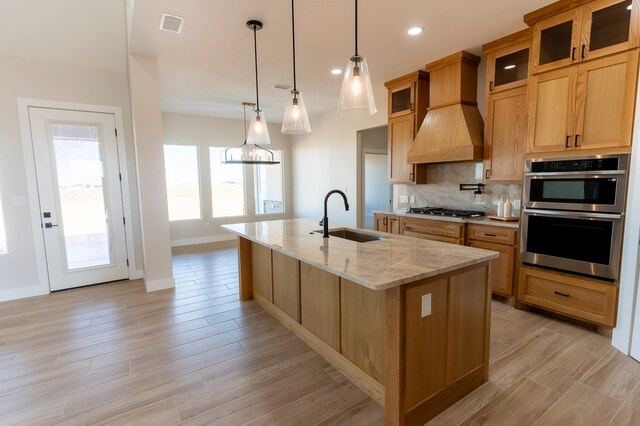 2209 S County Rd 1059, Midland, TX 79706 - kitchen with a sink, stainless steel appliances, a kitchen island with sink, tasteful backsplash, and light stone counters