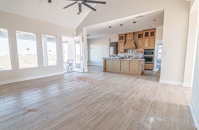 kitchen with stainless steel double oven, light wood finished floors, high vaulted ceiling, a ceiling fan, and open floor plan