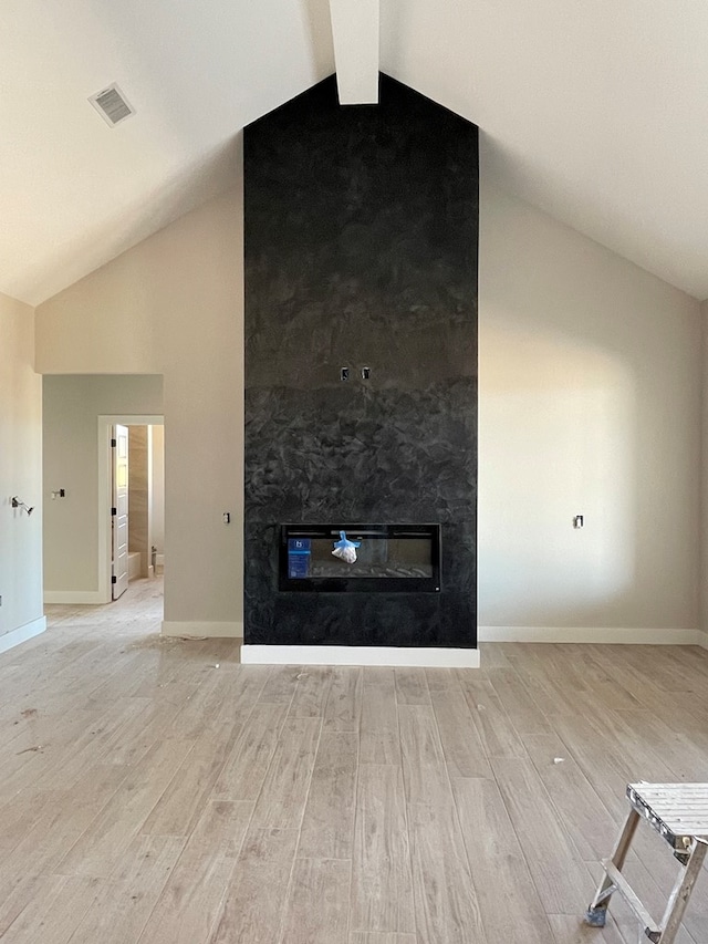 unfurnished living room with visible vents, light wood-style flooring, vaulted ceiling, and a fireplace