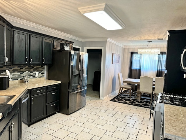 kitchen featuring pendant lighting, appliances with stainless steel finishes, backsplash, a notable chandelier, and crown molding