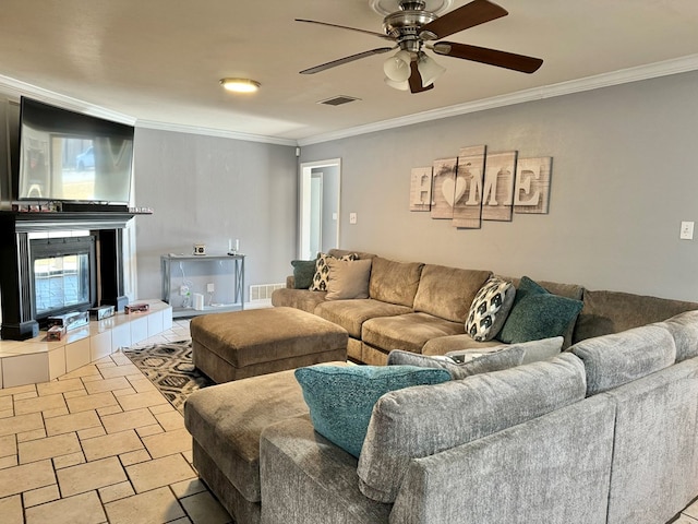 living room featuring ceiling fan, a tile fireplace, crown molding, and light tile patterned flooring