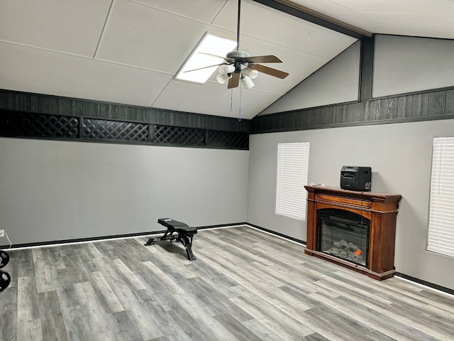 interior space featuring ceiling fan, light hardwood / wood-style flooring, and vaulted ceiling with beams